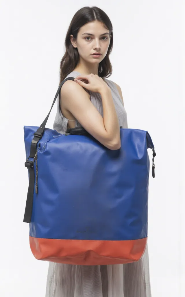 A French female model with a Waterproof bag, wearing a dress, against a white background, in a front   facing close   up